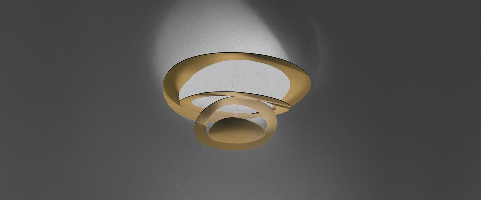 Elegant hotel room featuring Artemide Pirce Soffitto ceiling lamp with spiral white design, warm lighting, king bed, and sunset view