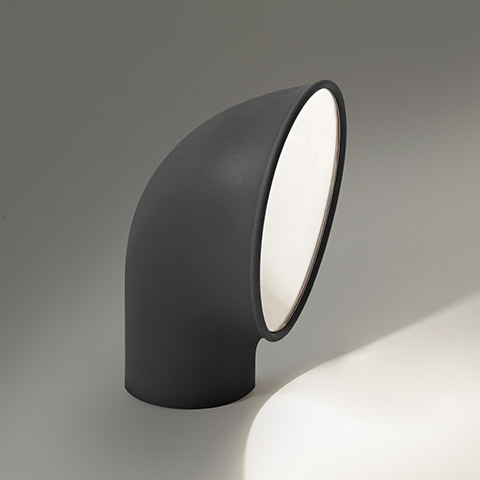 Lampada da terra per esterni Artemide Piroscafo: corpo tubolare curvo grigio scuro inclinato verso l'alto, con diffusore circolare bianco che emette luce concentrata