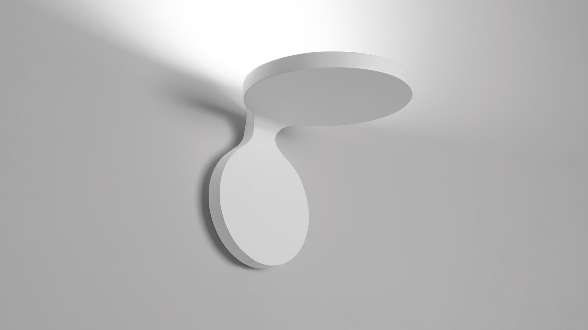 Lampada da soffitto Artemide Rea: corpo ovale bianco con rosone circolare, emette luce indiretta diffusa verso l'alto