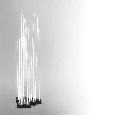 Lampada da terra Artemide Reeds IP20: molteplici aste luminose bianche di altezze variabili che si elevano da basi scure raggruppate