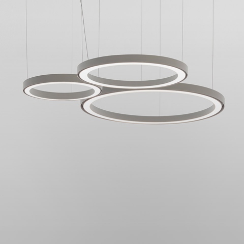 Three Artemide Ripple pendant lights: circular LED rings in grey, suspended at varying heights, sizes small, medium, and large