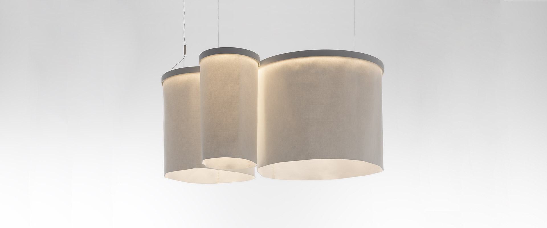 Lampada a sospensione Artemide Ripple: grande anello circolare bianco con luce LED integrata, sospeso da sottili cavi su sfondo blu scuro
