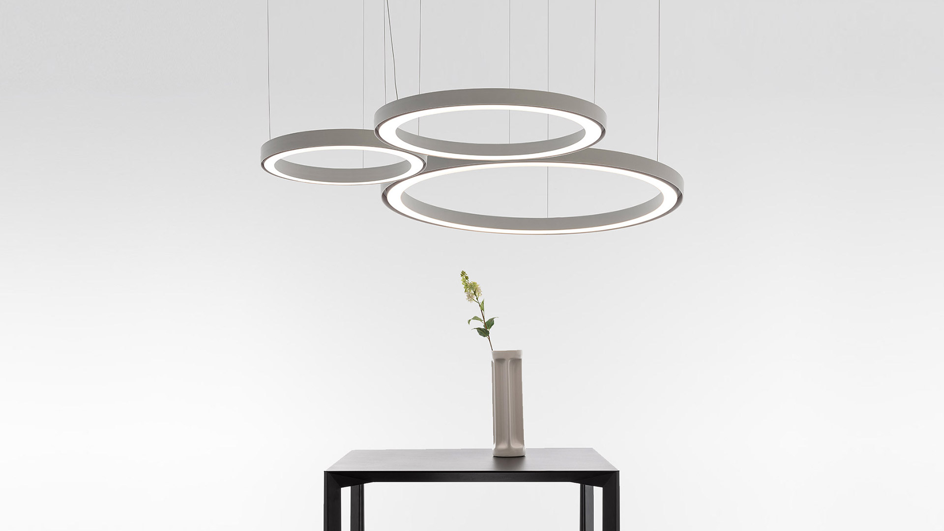 Lampada da soffitto Artemide Ripple: multipli anelli luminosi sovrapposti in finitura nera lucida che emettono luce LED bianca intensa su sfondo scuro