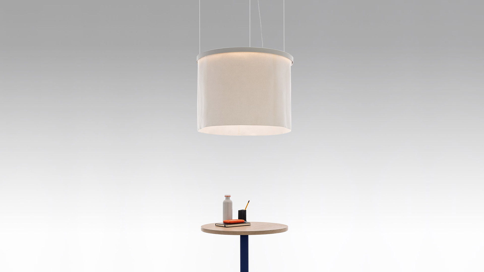 Tre lampade a sospensione Artemide Ripple con paralumi cilindrici in tessuto grigio caldo, disposte a cascata e con luce diffusa morbida