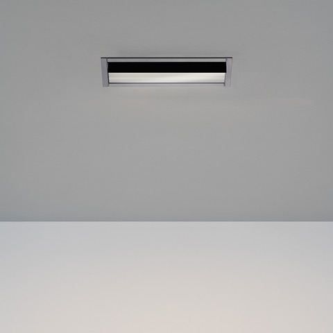 Luce da incasso a soffitto Artemide Sharp Wallwasher con sottile cornice rettangolare nera e cromata che emette un fascio orizzontale diffuso