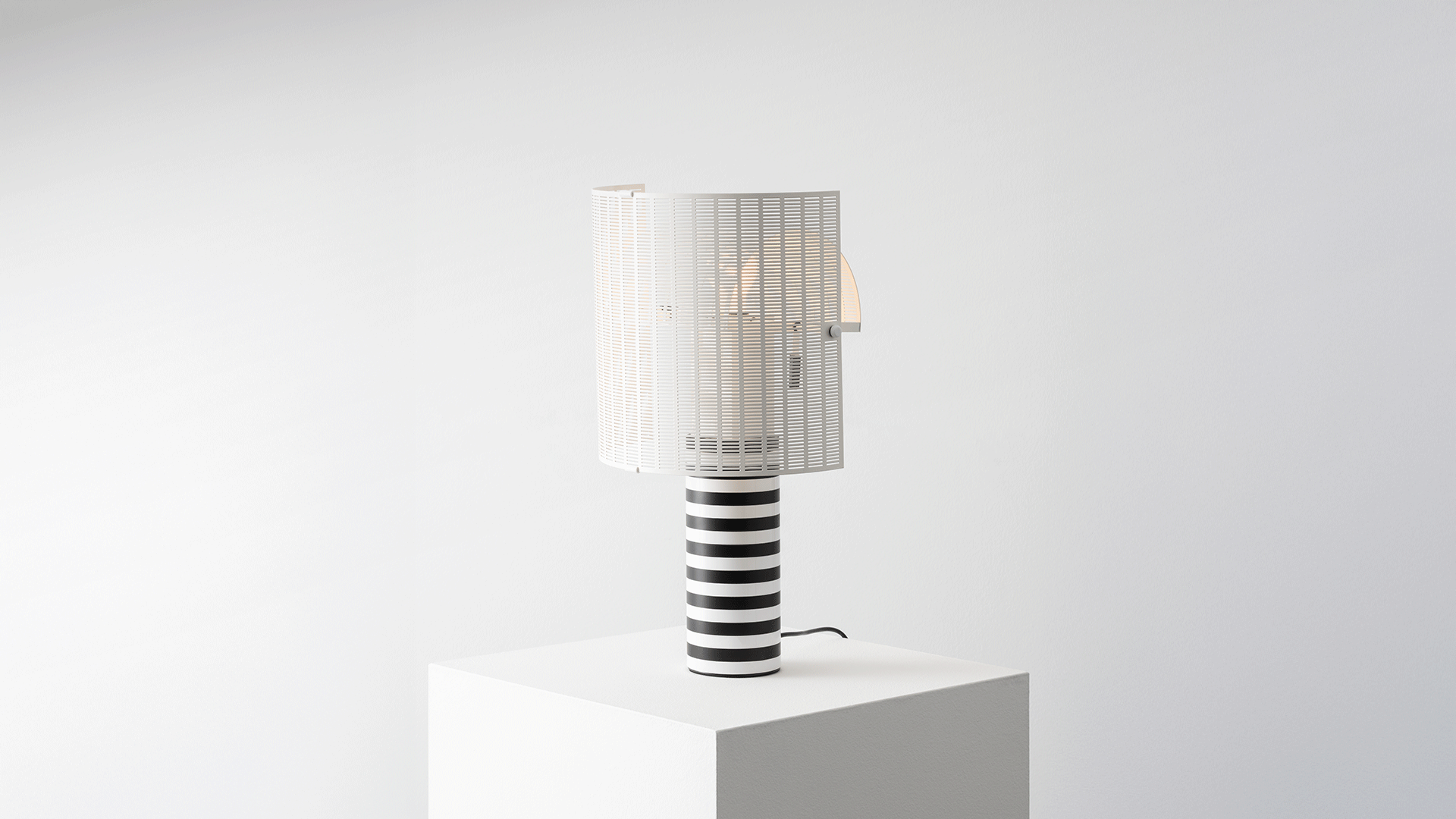 Dettaglio lampada da tavolo Artemide Shogun: base cilindrica con decise strisce orizzontali bianche e nere e paralume bianco a lamelle