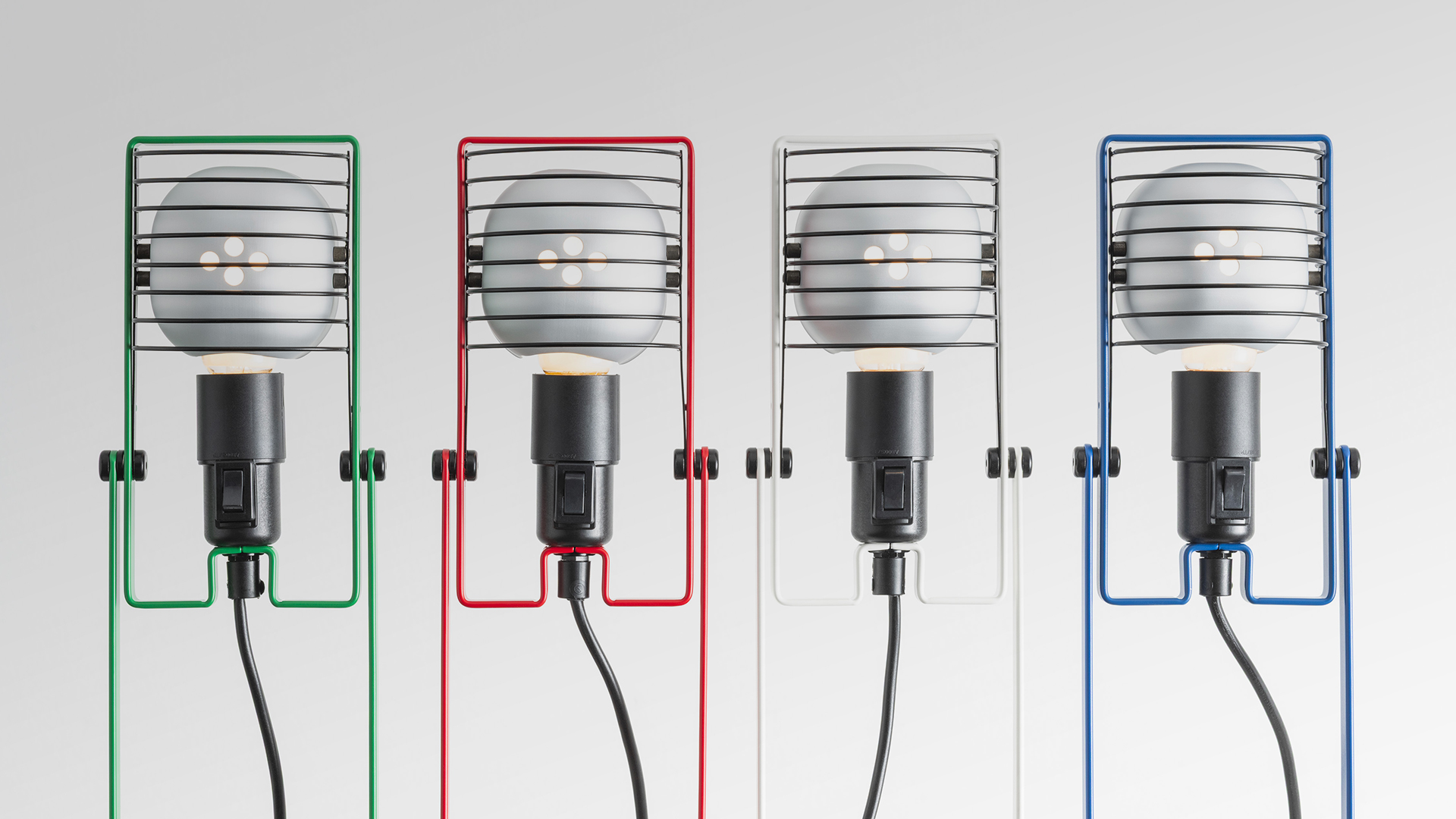 Assemblaggio della lampada Artemide Sintesi su banco di lavoro in fabbrica, con supporto blu regolabile, componenti e strumenti industriali sullo sfondo