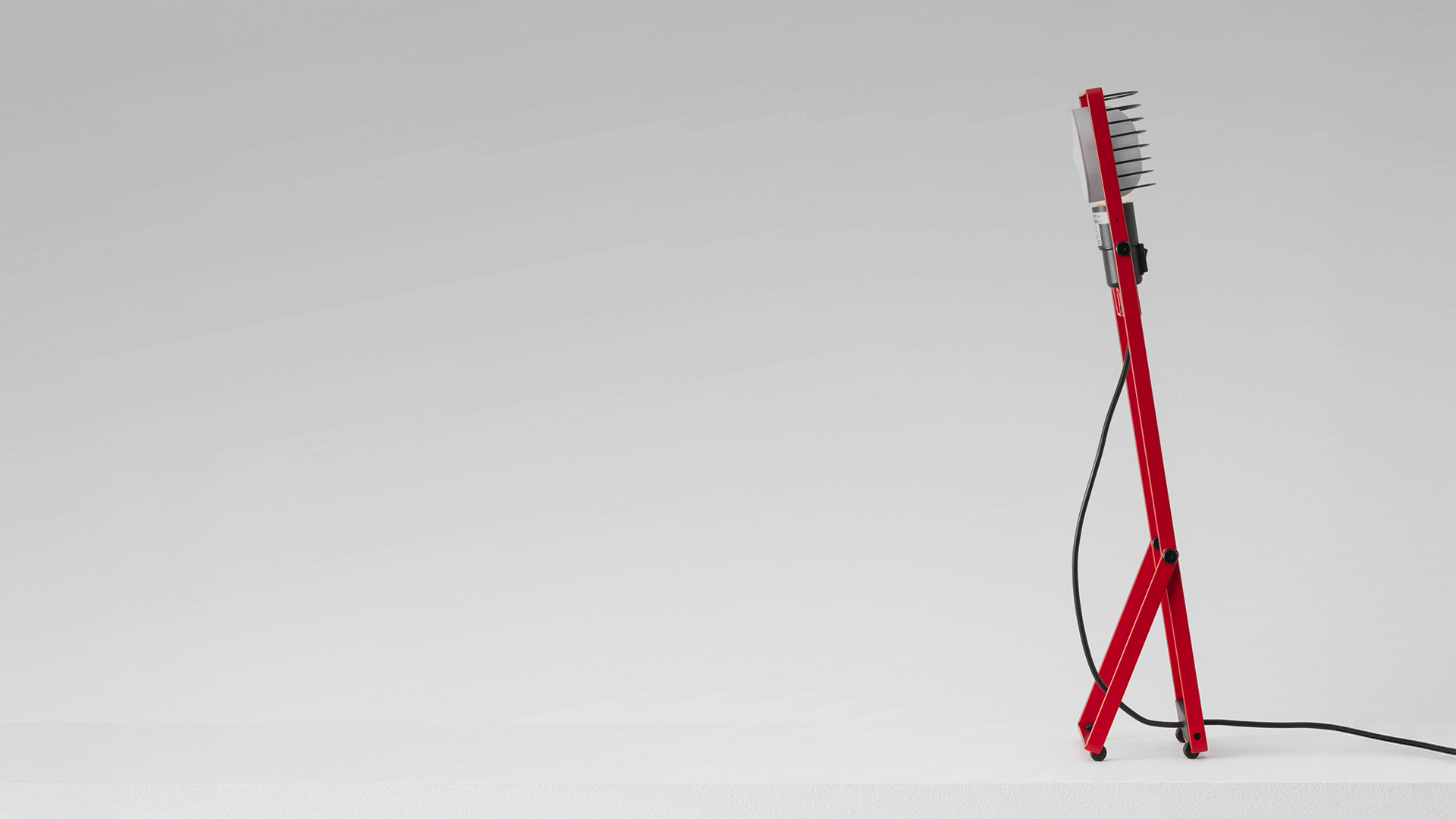 Lampada da tavolo Artemide Sintesi in rosso su una credenza vicino a una finestra, accanto a un giradischi, su parete rosso intenso