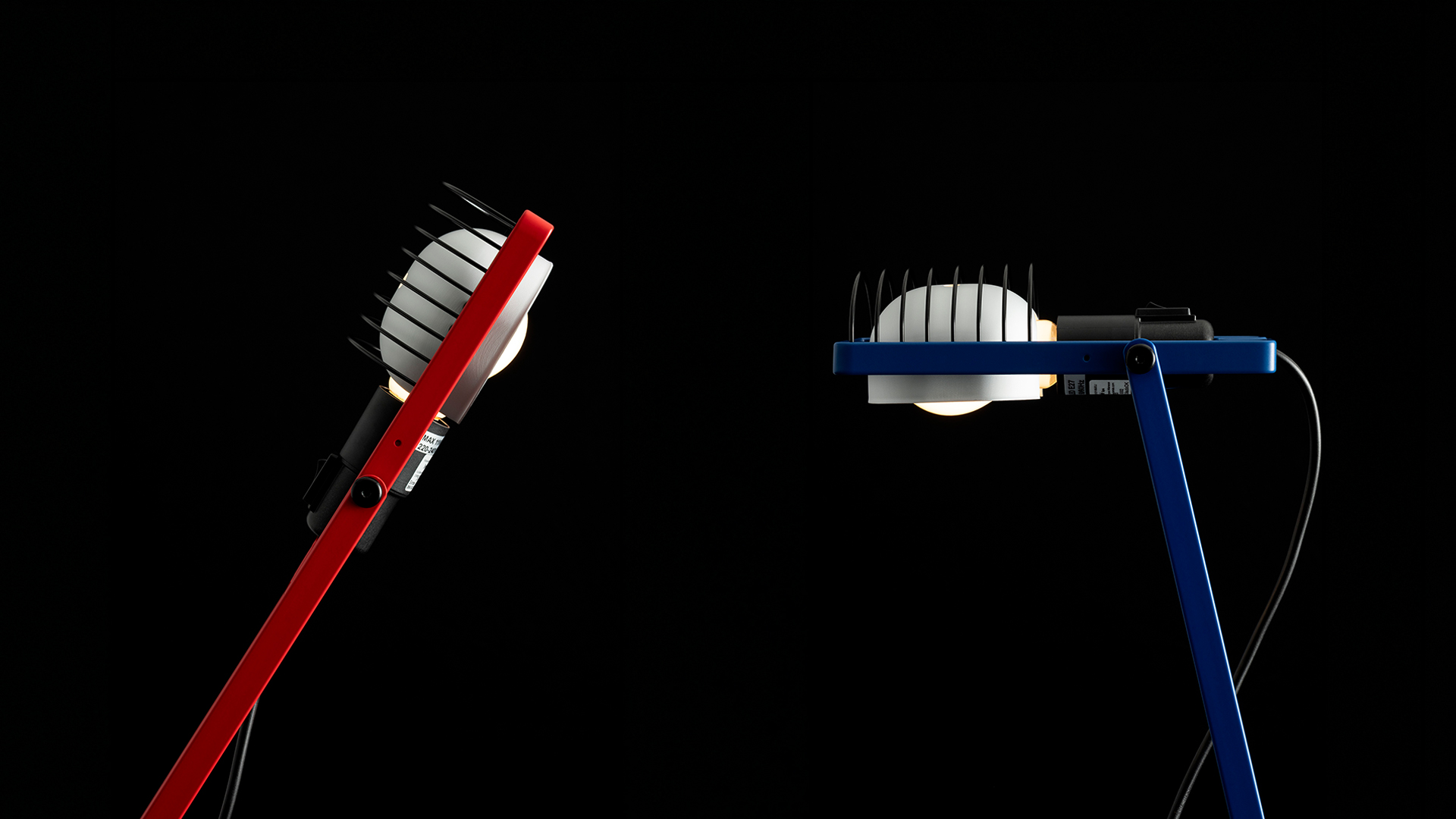 Lampada da tavolo Sintesi in blu con braccio articolato e testa LED a gabbia, montata su base bianca, illumina un libro aperto su scrivania bianca