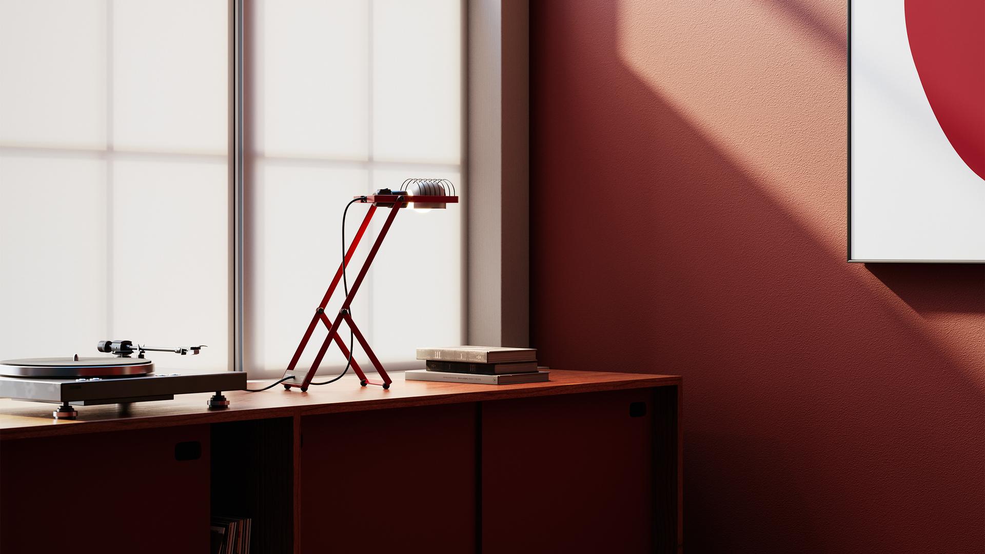 Lampada da tavolo Artemide Sintesi rossa con struttura metallica angolare, che illumina un libro aperto su sfondo verde