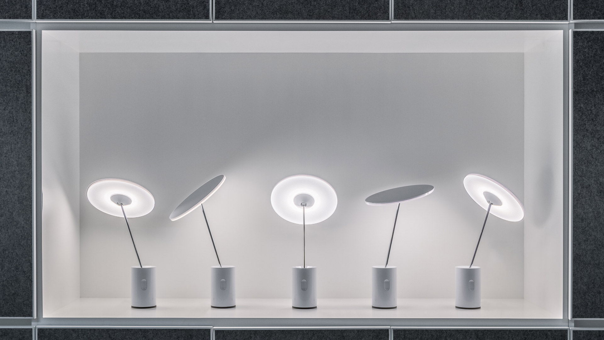 Five Artemide Sisifo table lamps displayed at varying angles, featuring circular white diffusers on slim stems with cylindrical marble bases