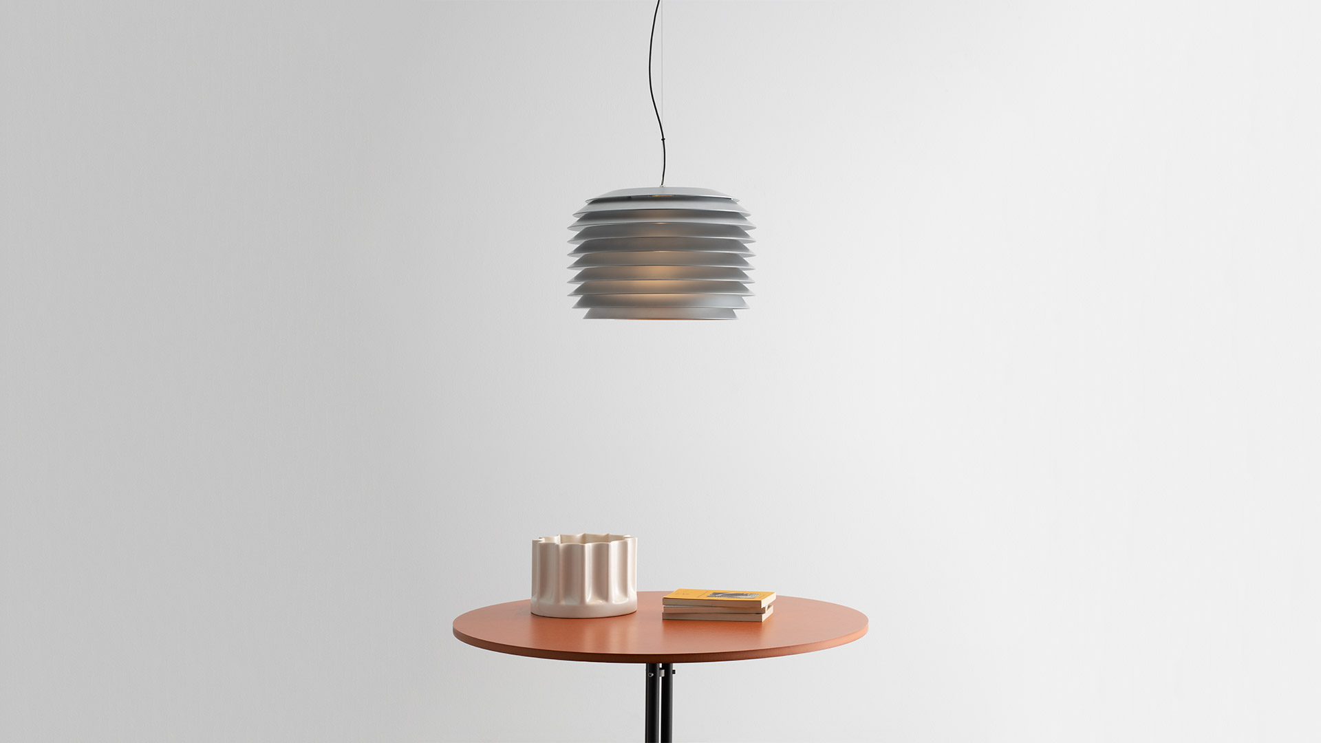 Lampade outdoor Artemide Slicing: sospensioni e segnapasso cilindrici scanalati tra erbe ornamentali su sfondo di listelli in legno