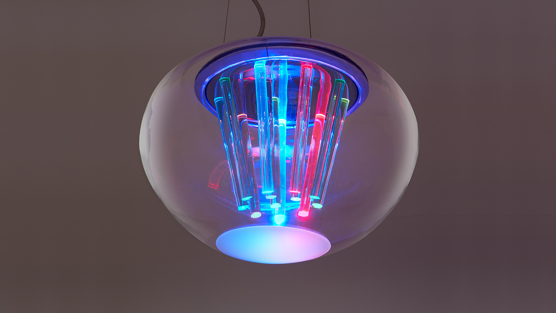 Lampada a sospensione Artemide Spectral Light: globo sferico in vetro con tubi luminosi RGB multicolore che emettono luce blu, rossa e verde