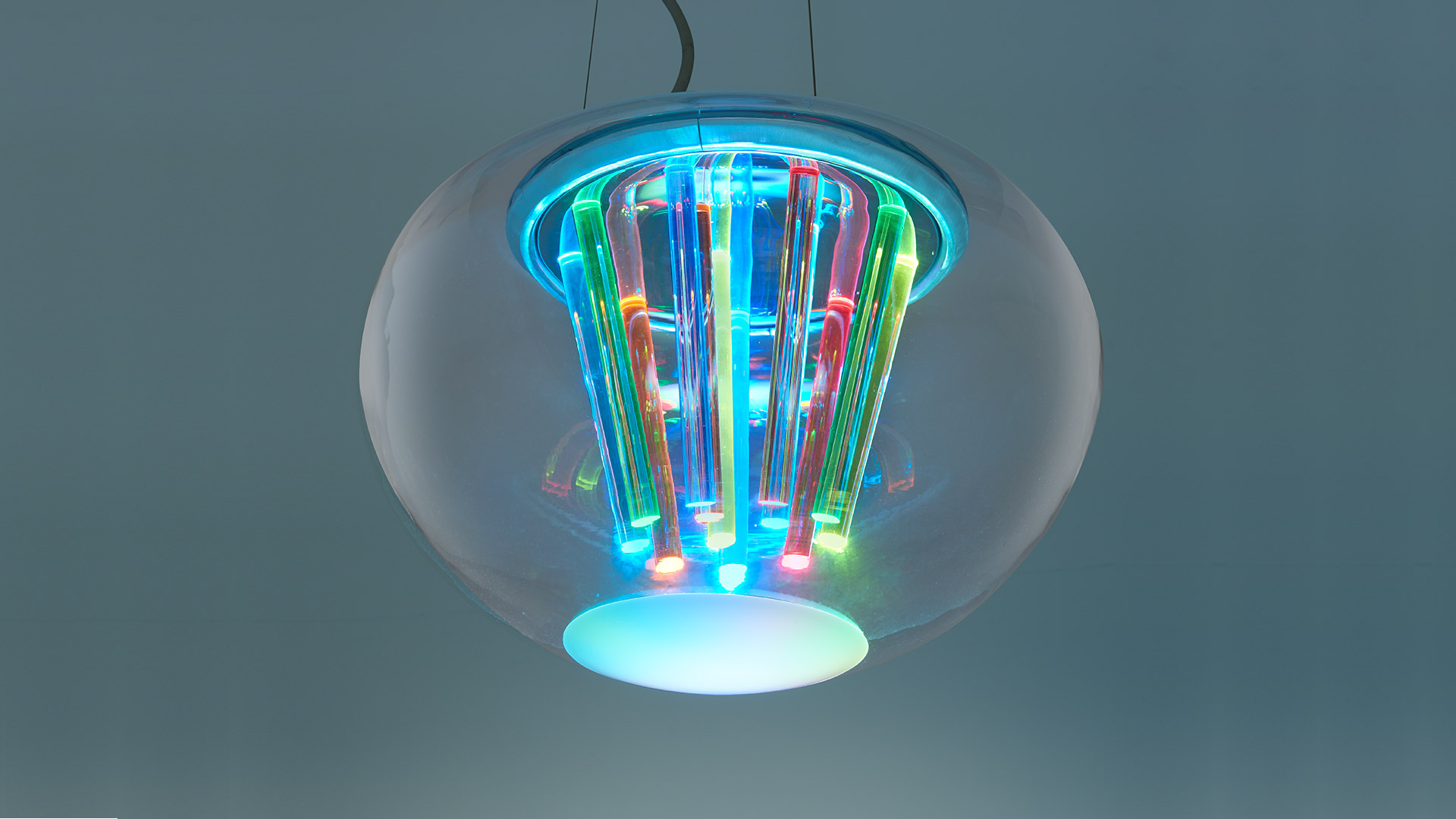 Lampada a sospensione Artemide Spectral Light: globo in vetro trasparente con tubi LED multicolori ed effetti luminosi ciano e RGB