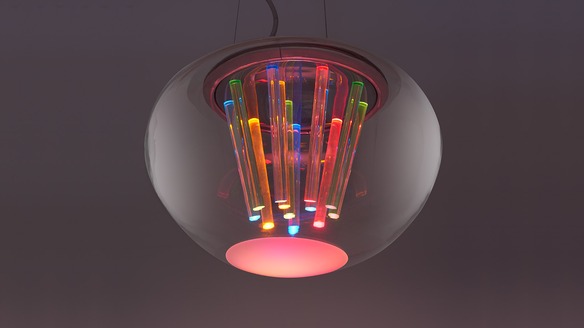 Lampada a sospensione Artemide Spectral Light: globo in vetro traslucido con tubi luminosi multicolore che emettono luce RGB verso il basso