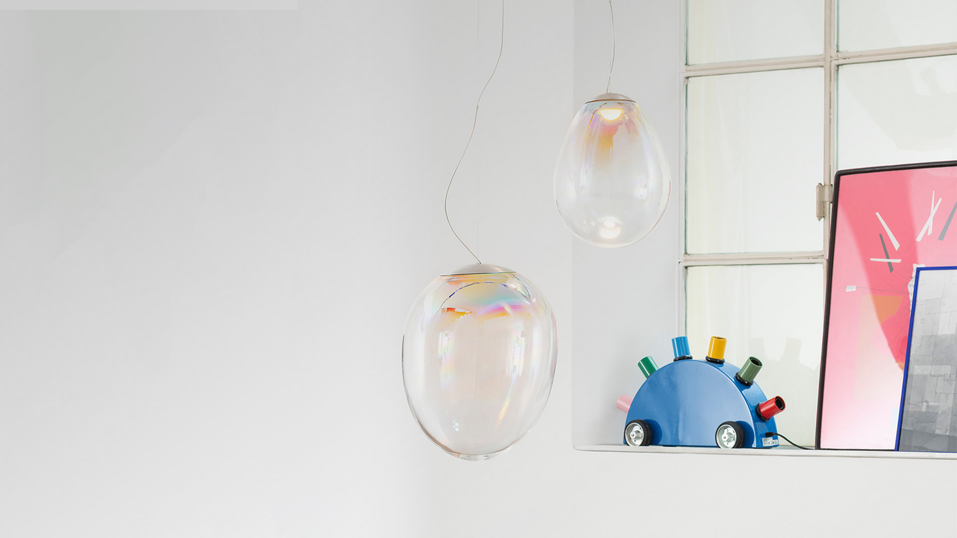 Quattro lampade a sospensione Artemide Stellar Nebula: diffusori ovali in vetro trasparente con riflessi iridescenti multicolore, appese a sottili cavi