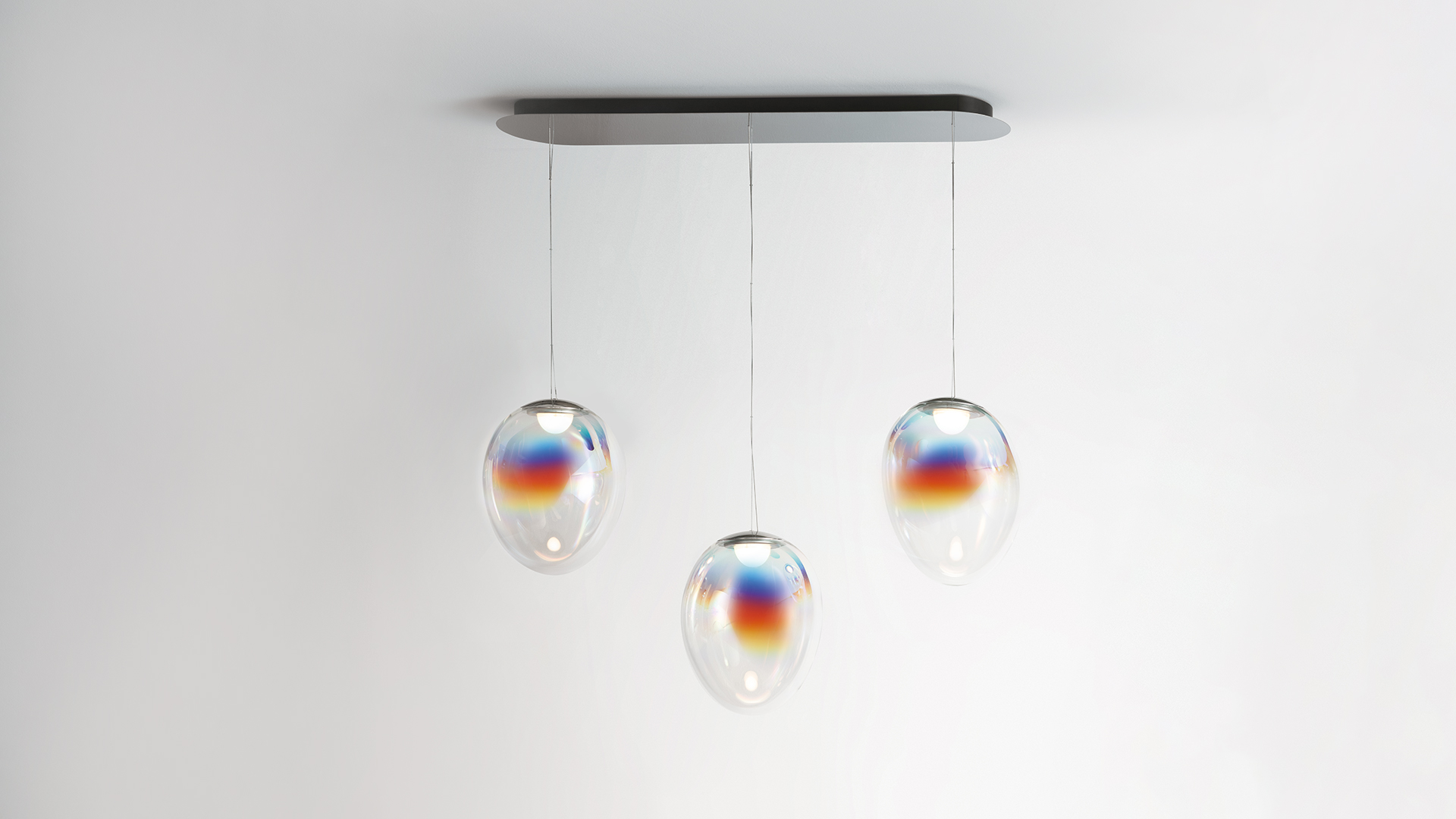 Lampada da tavolo Stellar Nebula: diffusore in vetro a forma di uovo iridescente con riflessi arcobaleno su base dorata, sfondo verde acqua