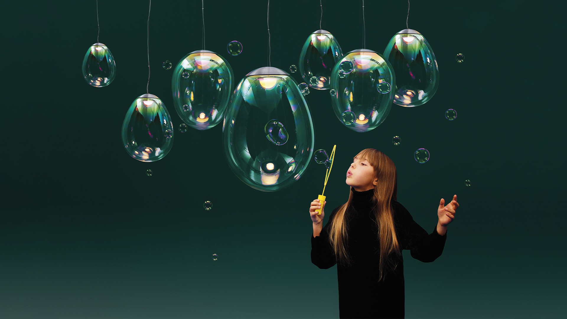 Due lampade a sospensione Artemide Stellar Nebula con diffusori in vetro soffiato iridescente dai riflessi colorati interni, appese su parete bianca