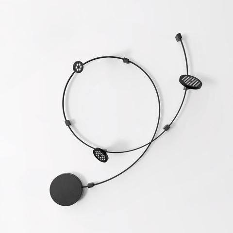 Artemide Sylt Stand Alone: sistema a cavo circolare nero con un disco pieno e due moduli LED ovali forati su sfondo bianco