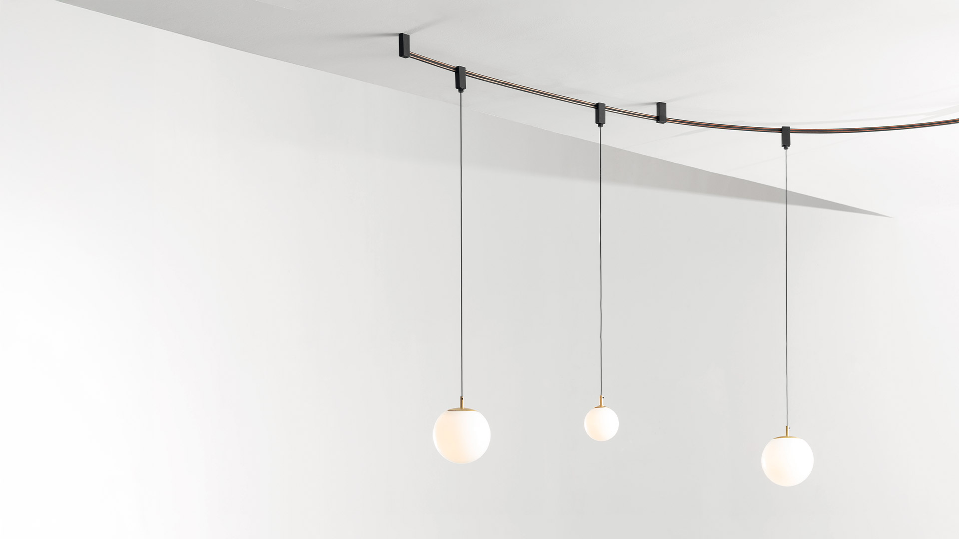 Due faretti cilindrici orientabili neri Artemide Sylt montati su un sistema a cavo flessibile, che emettono luce bianca calda