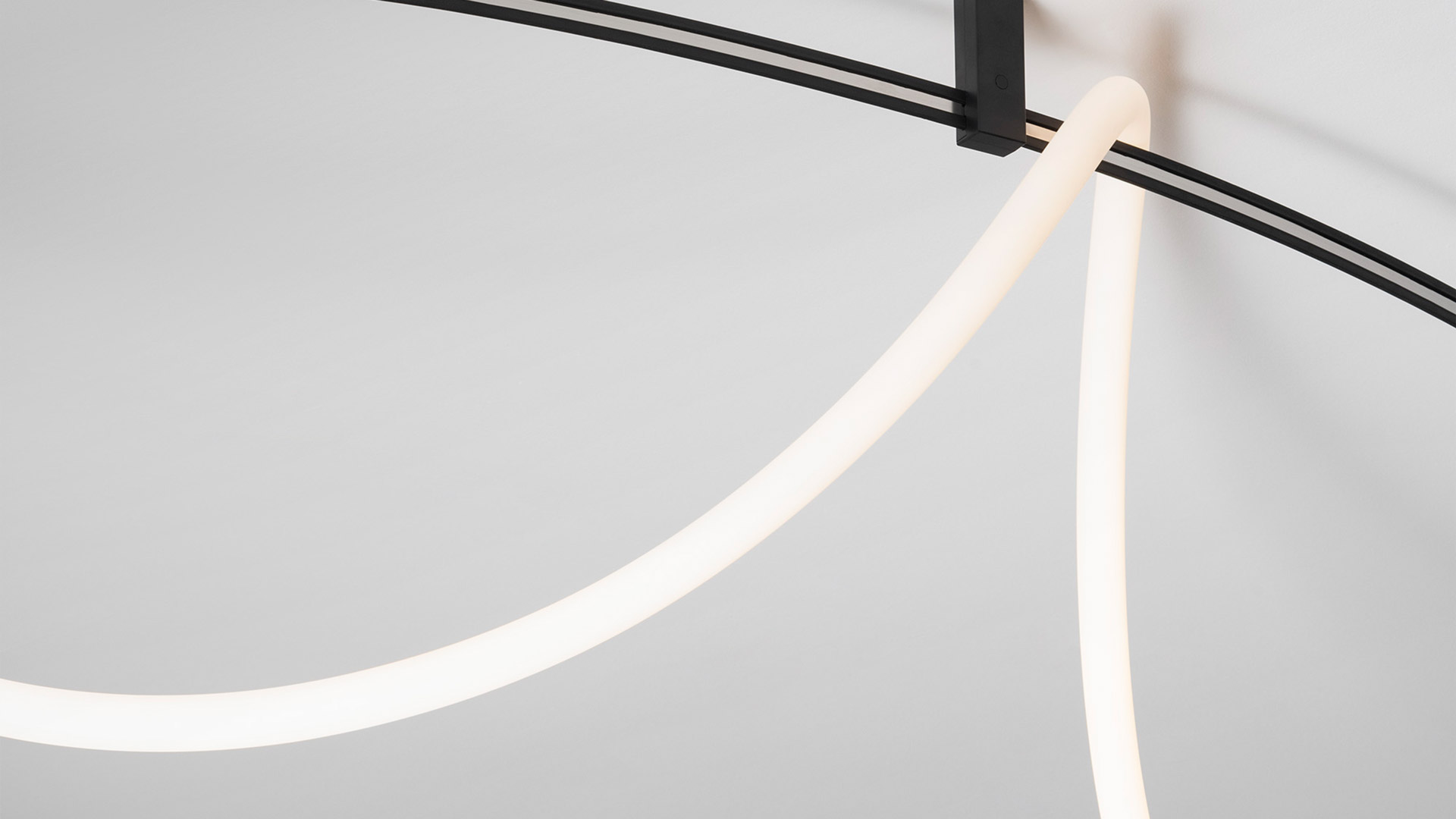Sistema di illuminazione su binario Artemide Sylt in nero: due faretti orientabili e una barra LED lineare montati su cavo curvo