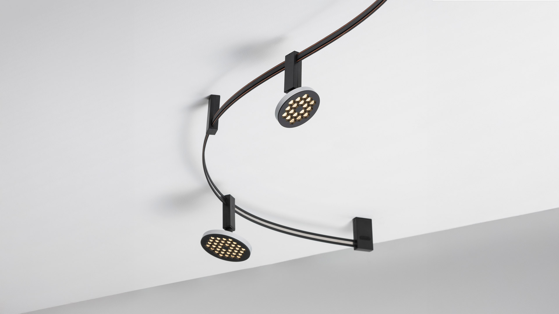 Illuminazione su binario Artemide Sylt: pendente LED lineare nero opaco sospeso da una guida a soffitto tramite staffa rettangolare