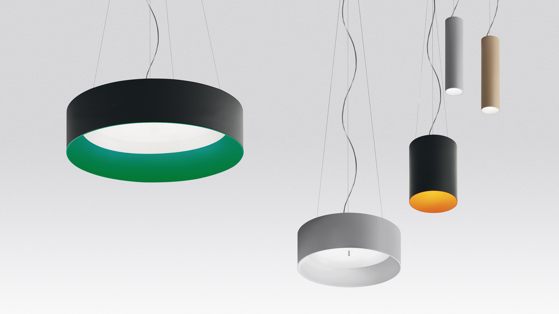 Lampade a sospensione Artemide Tagora: grande anello nero con interno verde, cilindro medio grigio e pendenti cilindrici sottili in grigio, nero-oro e beige