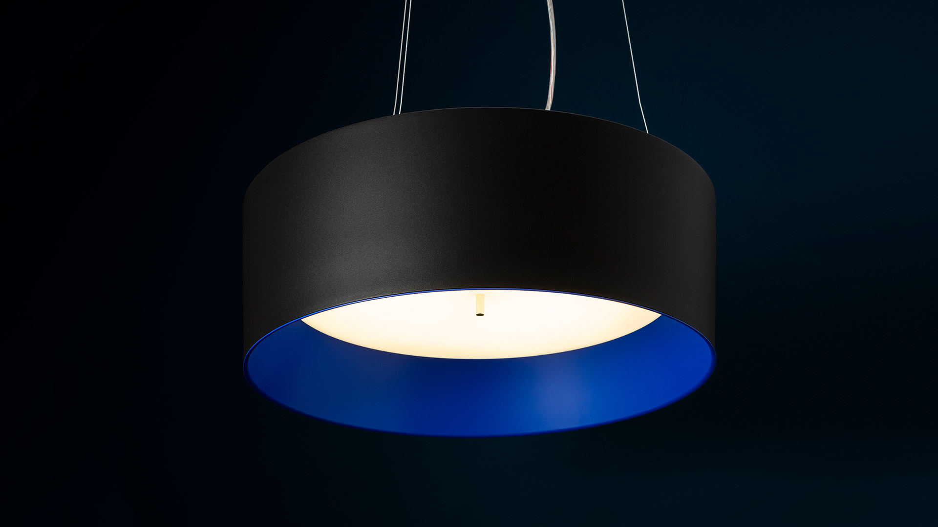 Lampada a sospensione Tagora Sospensione 570: paralume esterno cilindrico nero opaco con diffusore interno blu vivido che emette luce bianca calda