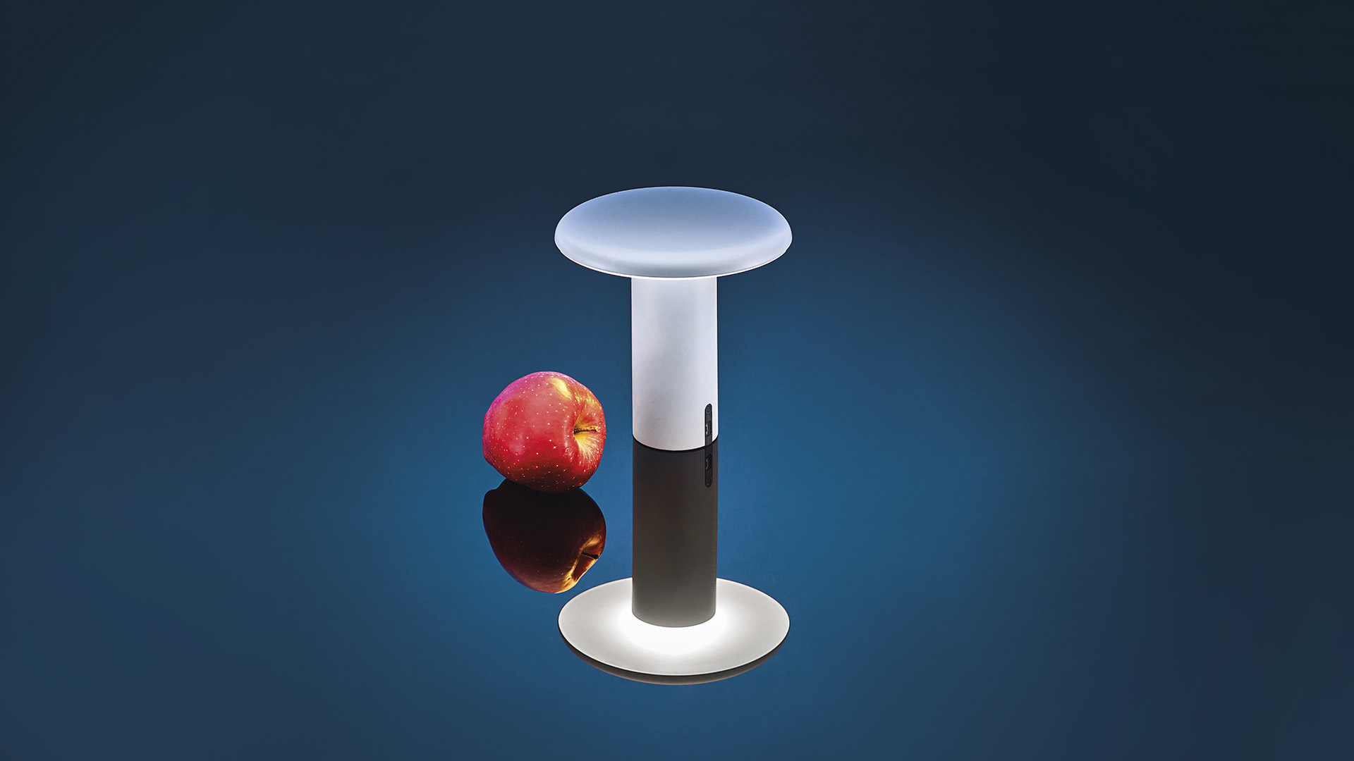 Six Artemide Takku portable table lamps in mushroom shape, displayed in green, white, black, taupe, red-orange, and navy blue