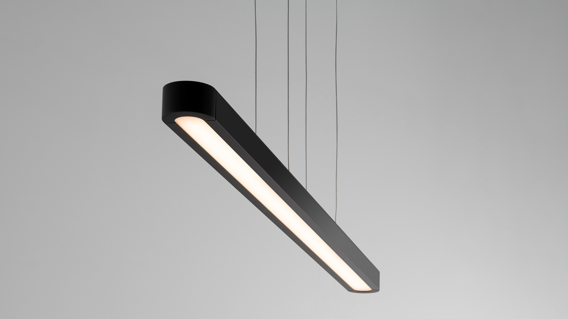 Lampada a sospensione Talo di Artemide: profilo allungato in alluminio con luce LED bianca diffusa, sospesa al soffitto da sottili cavi