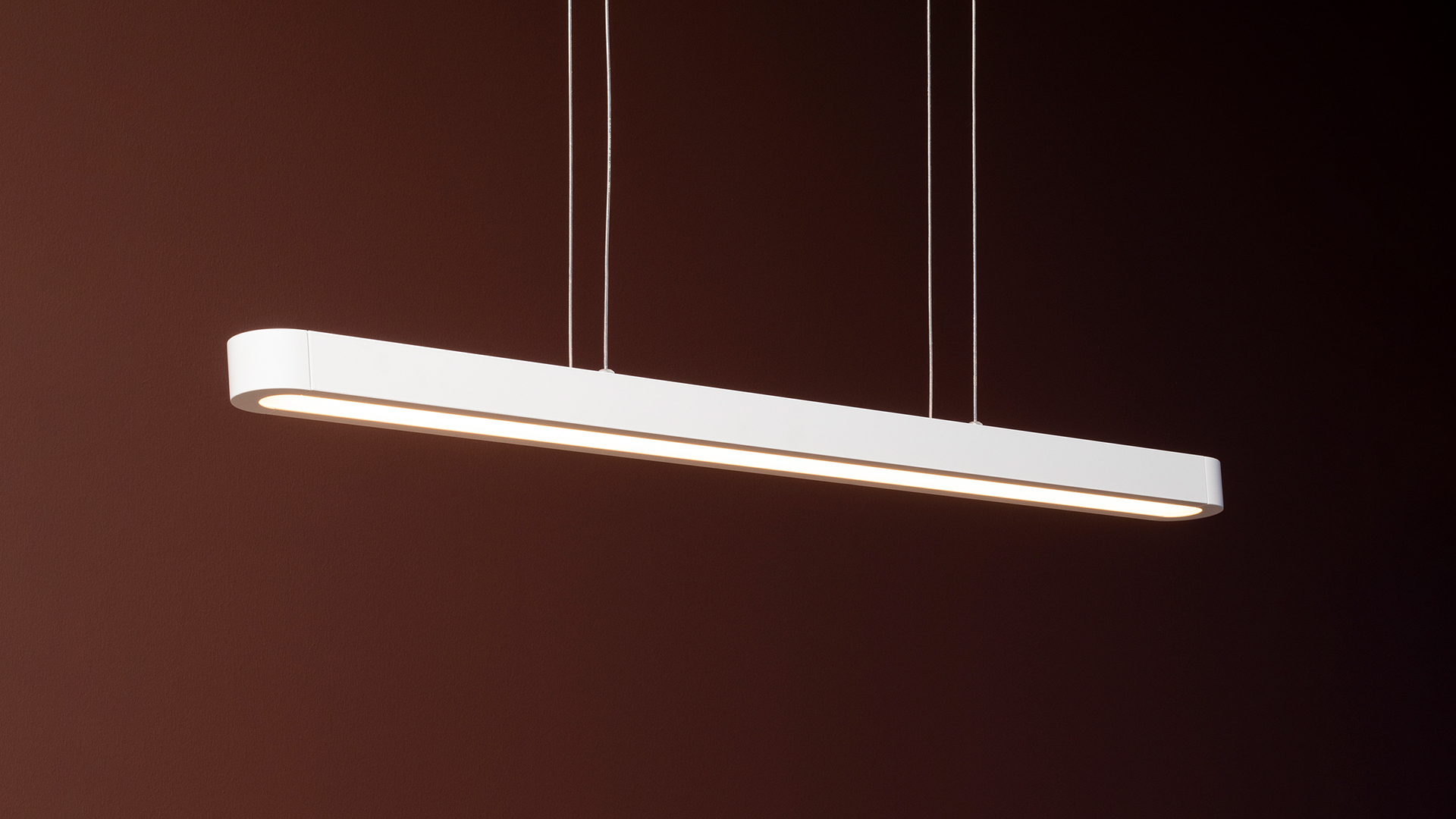 Lampade a sospensione Talo di Artemide: tre sottili pendenti lineari LED neri appesi a diverse altezze su cavi sottili