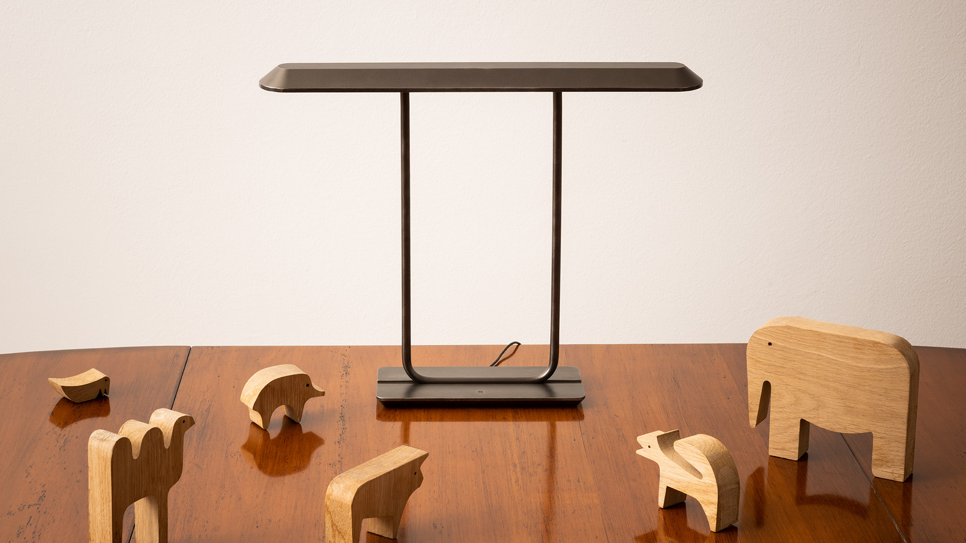 Lampada da tavolo Artemide Tempio con paralume rettangolare scuro su sottile struttura nera, esposta su credenza in legno stile mid-century con vaso decorativo