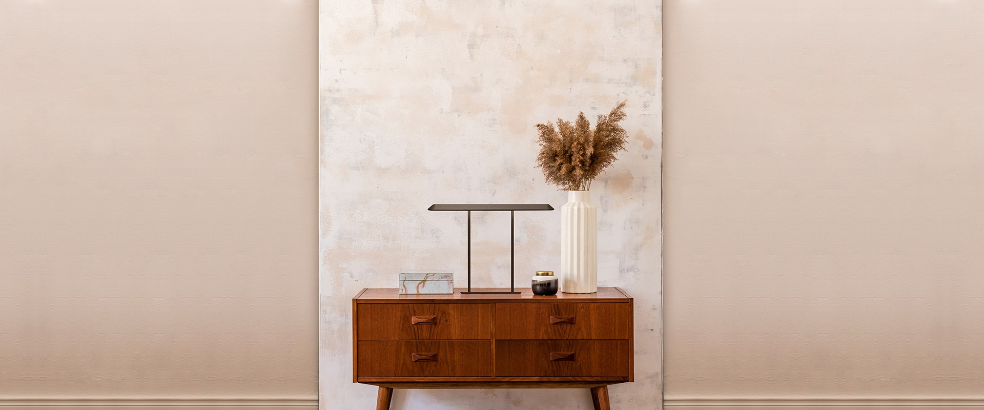 Lampada da tavolo Artemide Tempio in finitura bronzo scuro, struttura metallica a U minimalista con paralume rettangolare piatto, su superficie in legno con giocattoli in legno