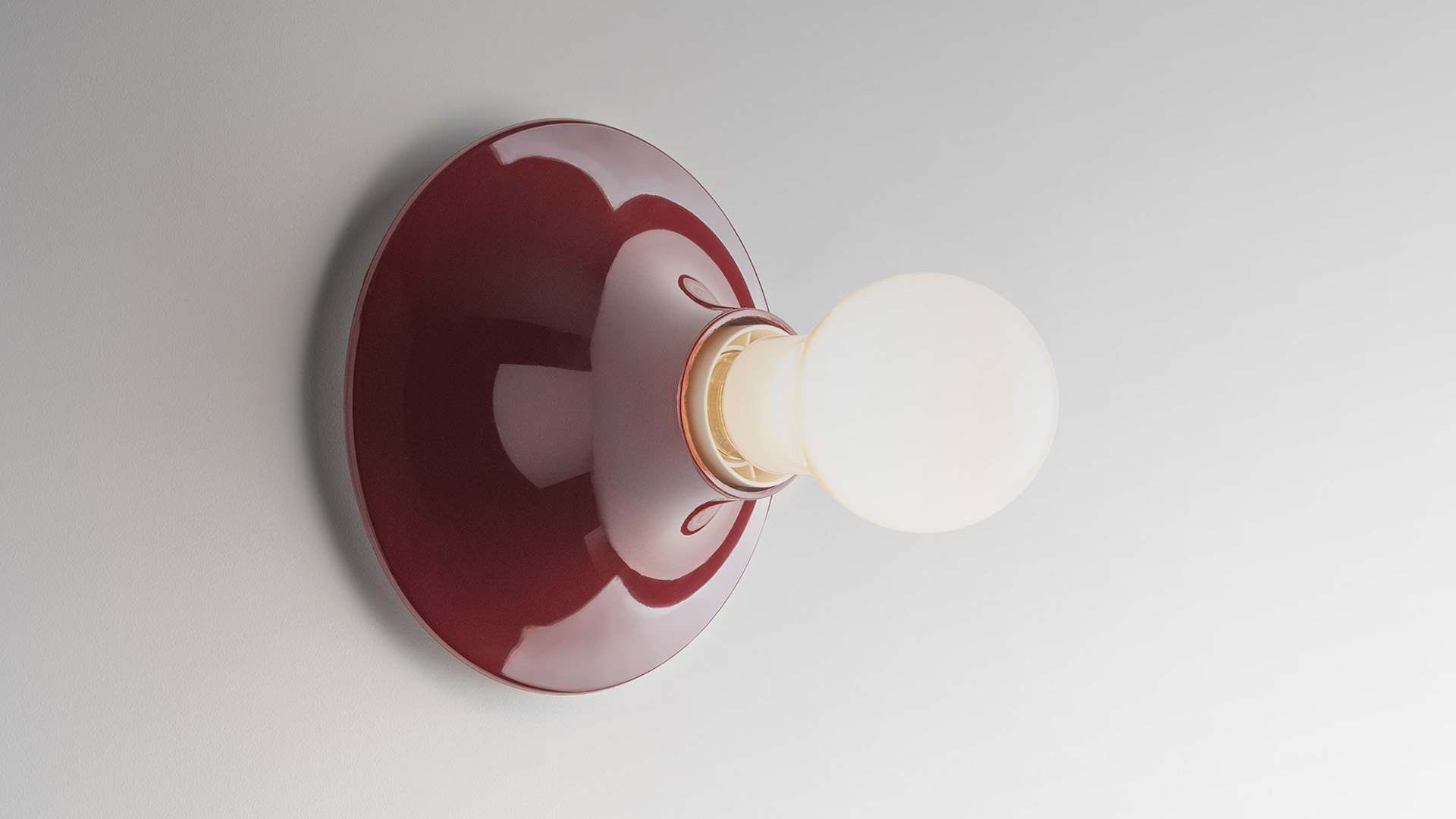 Artemide Teti wall lamp in cobalt blue ceramic with exposed frosted Edison bulb, mounted on a circular base