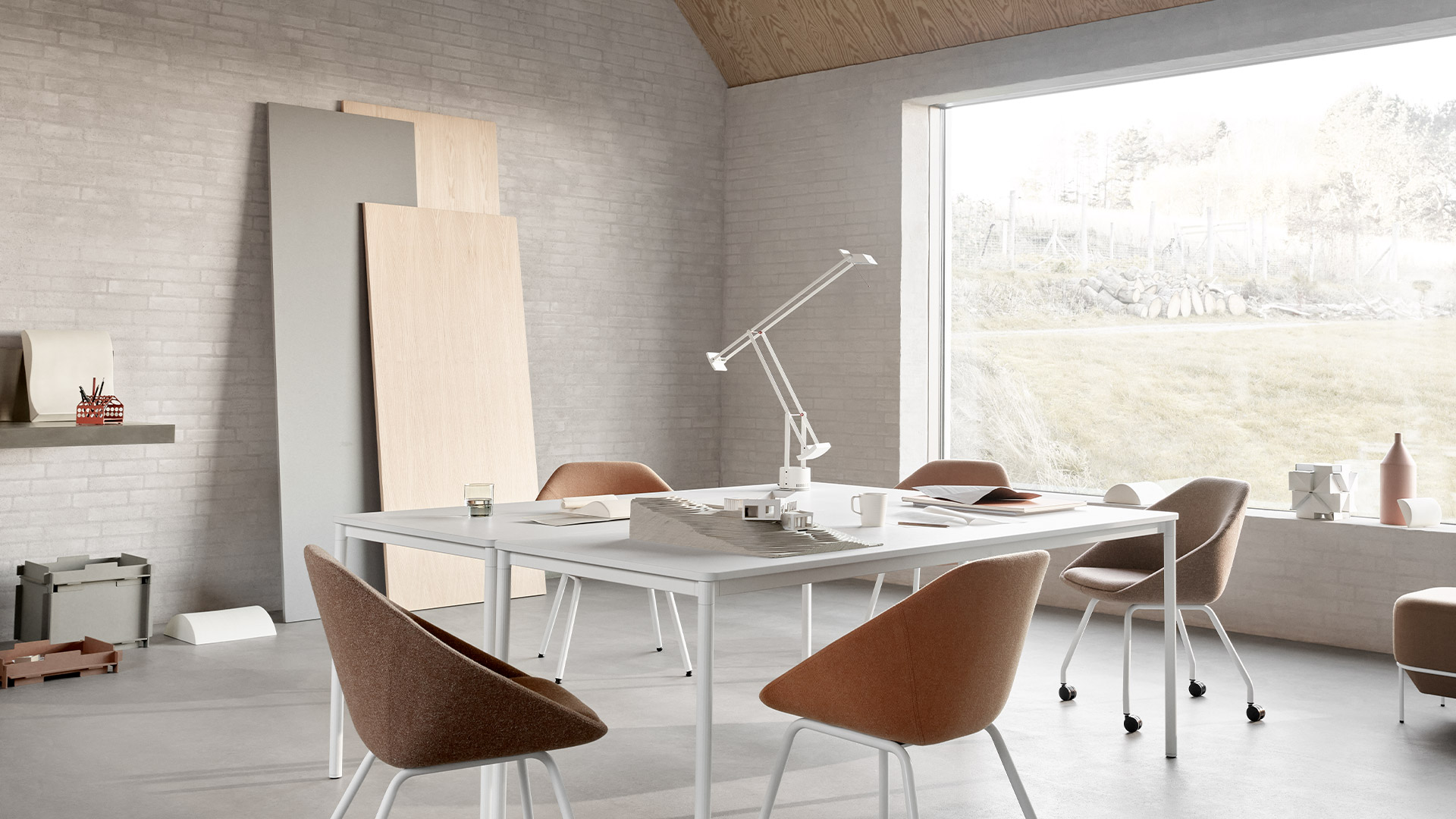 Lampada da tavolo Artemide Tizio nera con braccio articolato su una scrivania in legno, circondata da libri, matite e foto appese.