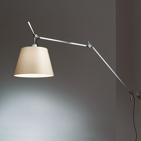 Lampada da parete Artemide Tolomeo Mega Parete con braccio in alluminio regolabile e ampio paralume in tessuto beige, montata su parete grigia
