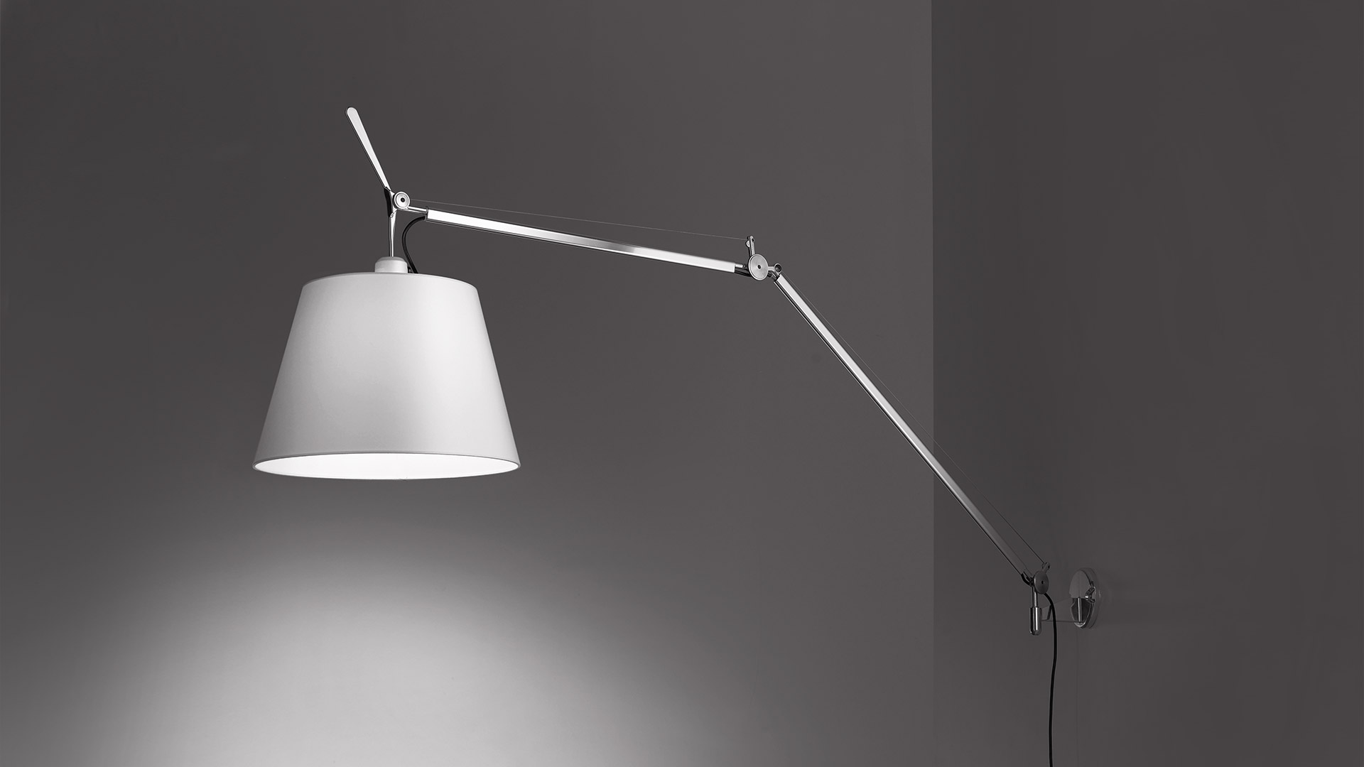 Lampada da parete Artemide Tolomeo Mega Parete con braccio in alluminio regolabile e grande paralume conico bianco, montata su parete grigia