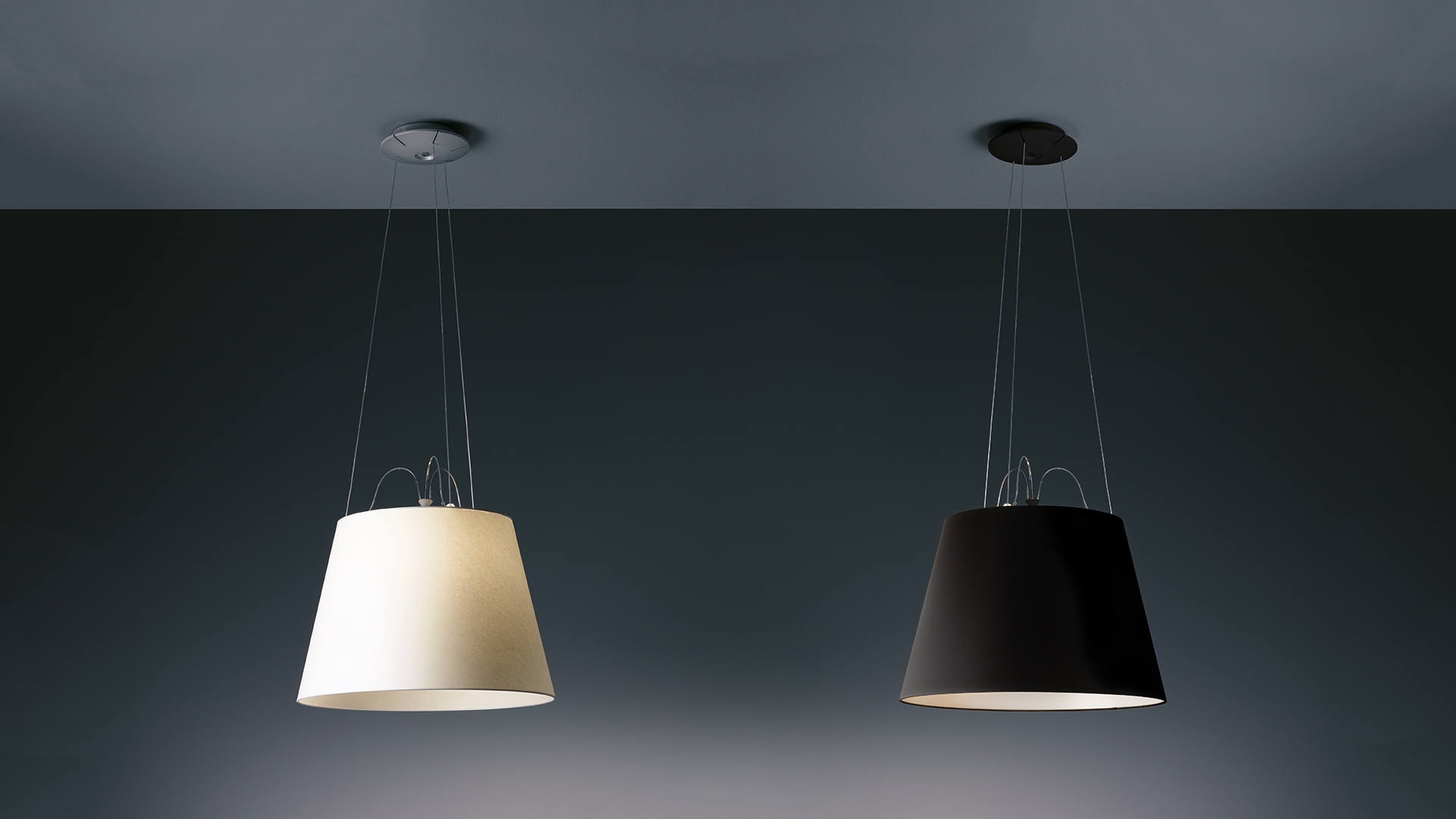 Due lampade a sospensione Artemide Tolomeo Mega Sospensione: paralume conico bianco avorio a sinistra, paralume conico nero opaco a destra, sospese da sottili cavi