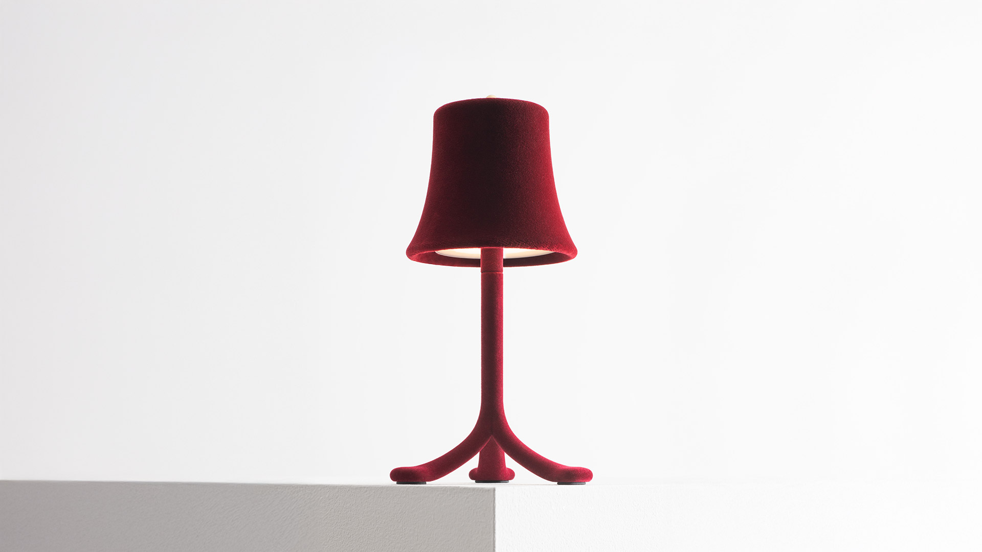 Primo piano della lampada da tavolo Artemide Trois Rois con paralume a campana in velluto rosso intenso e stelo coordinato, base LED luminosa
