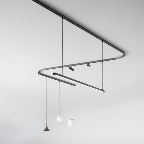Artemide Turn Around System: curved dark track on ceiling with spotlight, linear LED bar, and three pendant lights including globe and cone shades