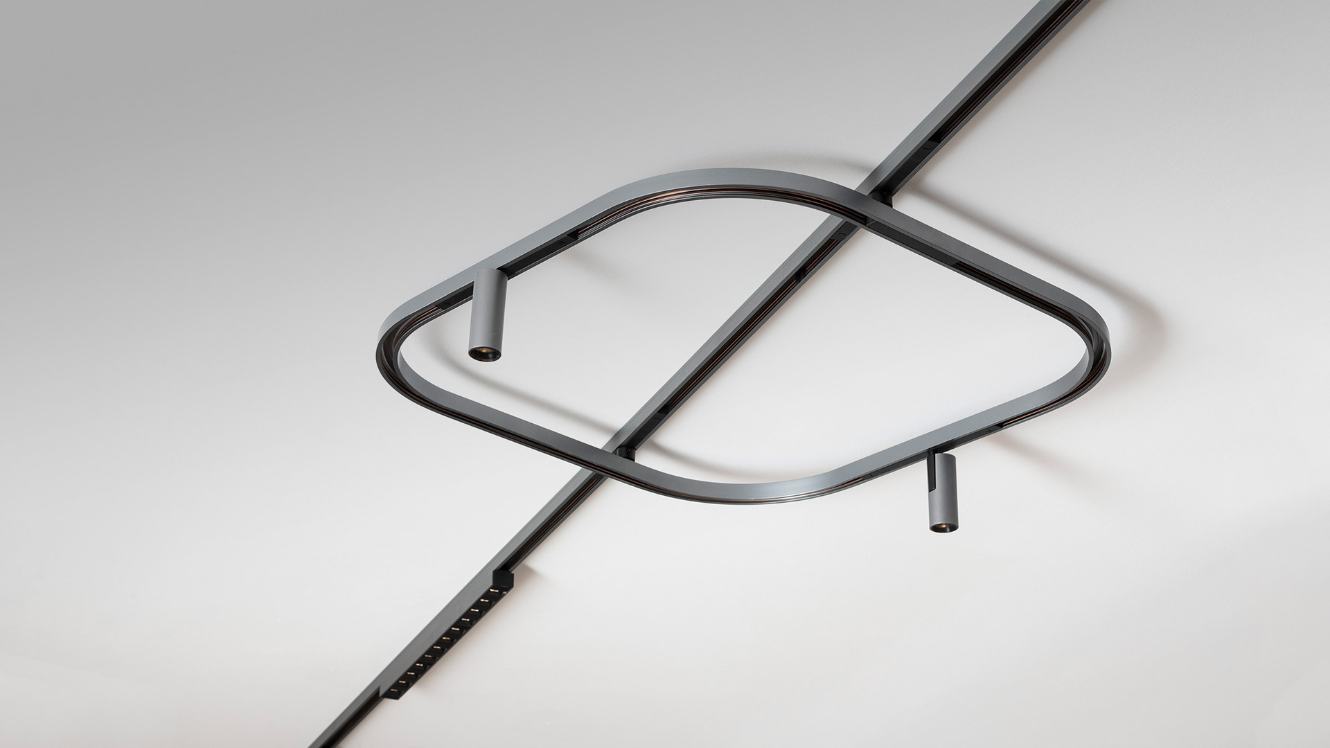 Artemide Turn Around System: striscia LED flessibile in profilo argento, che curva lungo un angolo di parete con staffa di montaggio scura