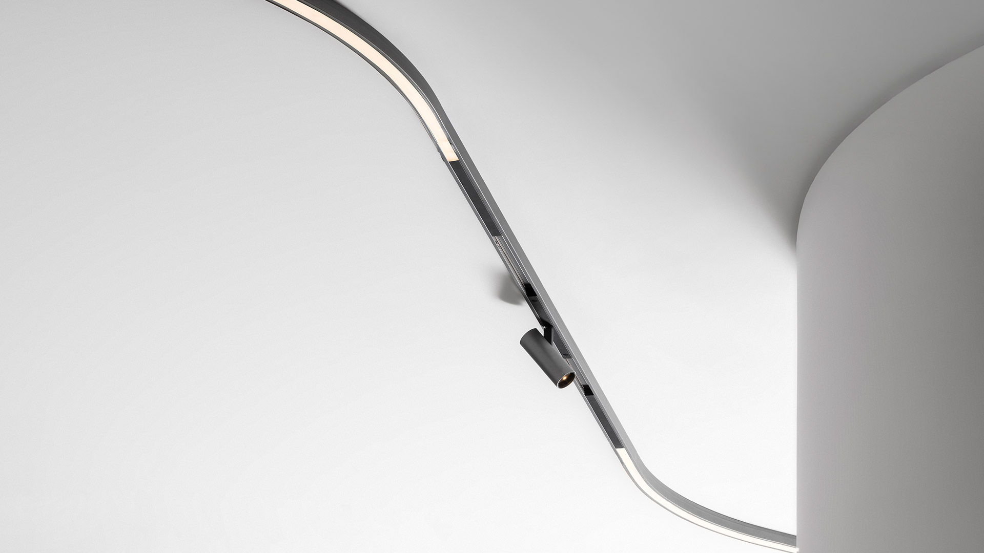 Sistema Artemide Turn Around: binario a soffitto curvo con più lampade a sospensione con diffusori sferici, cilindrici e rettangolari in bianco e nero