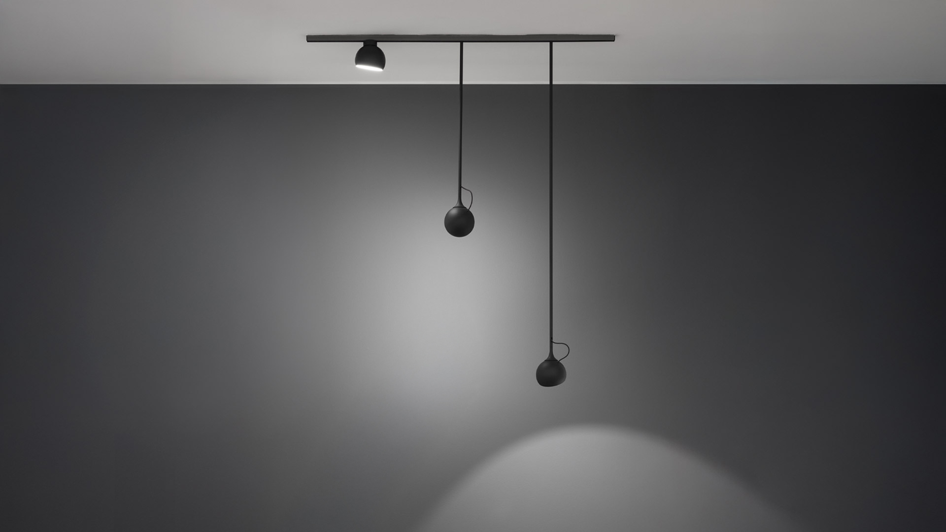 Artemide Turn Around System: binario nero a soffitto con uno spot e due teste sferiche a sospensione a diverse altezze