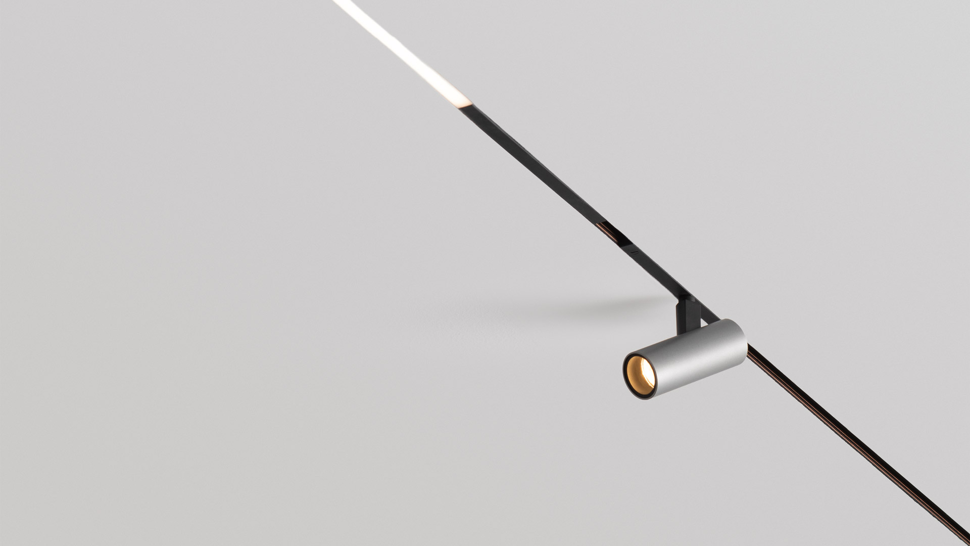 Sei lampade a sospensione Artemide Turn Around System su binario: diffusori sferici orientabili in bianco, blu scuro e uno giallo, a lunghezze variabili.