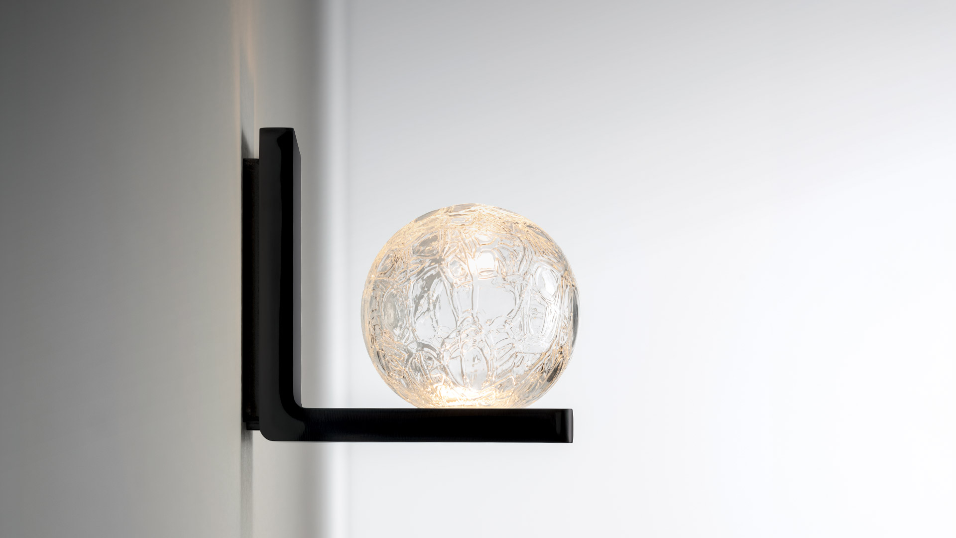 Applique da parete Artemide Ulrich und Diotima con diffusore a sfera in vetro lavorato su piastra rettangolare cromata, emette luce calda