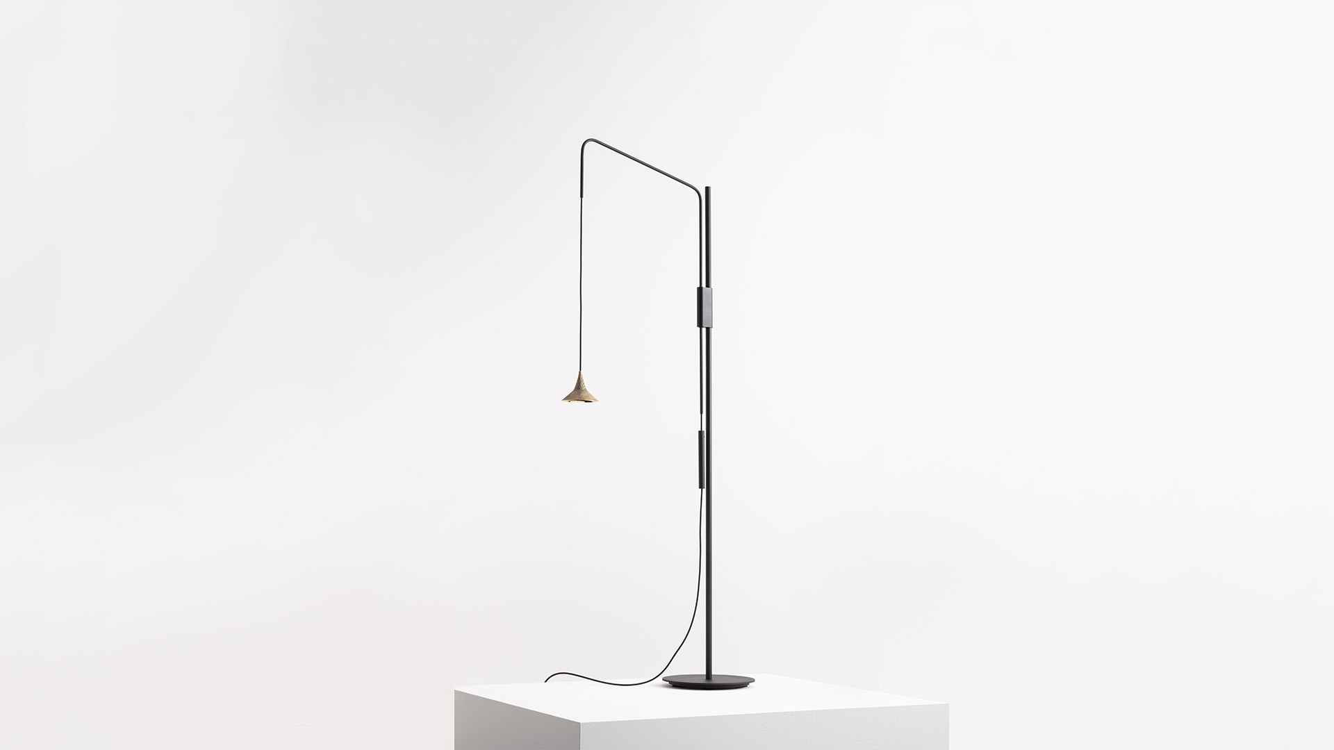 Due lampade a sospensione Artemide Unterlinden con paralumi conici scuri e texture su cavi neri, una accesa con luce LED bianco caldo