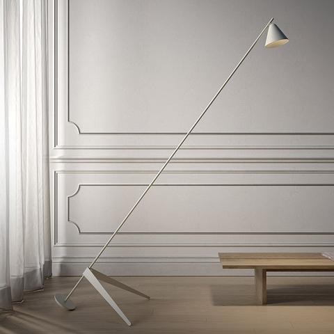 Lampada da terra Artemide Vea: sottile stelo diagonale bianco con paralume conico, base a treppiede, in una stanza classica con pannelli bianchi e tavolino in legno