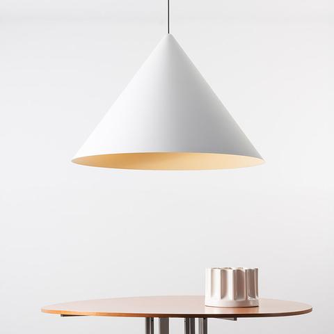 Lampada a sospensione Vea di Artemide: paralume conico bianco con interno dorato caldo, appesa sopra un tavolo rotondo in legno