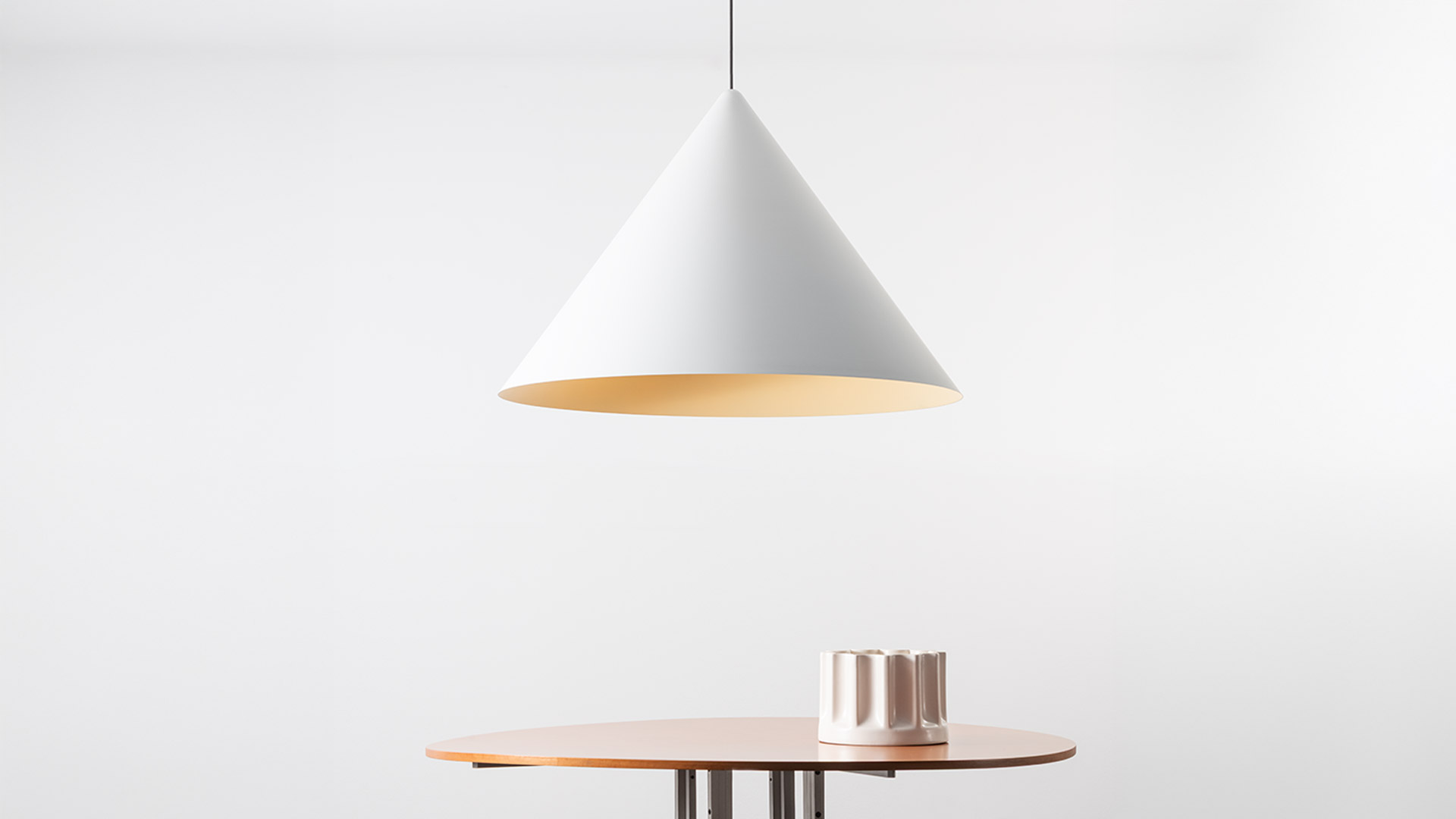 Lampada a sospensione Artemide Vea con paralume conico bianco e interno dorato caldo, appesa sopra un tavolo rotondo in legno.