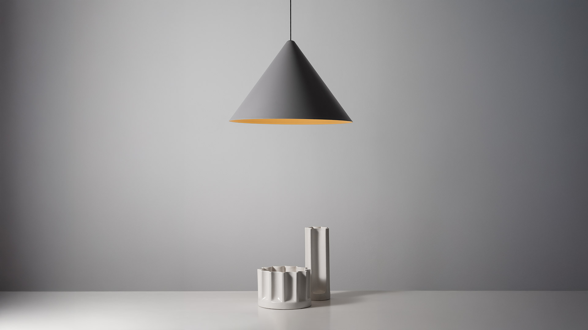 Artemide Vea Sospensione: donna tocca il fondo piatto del disco mostrando l'interno dorato, abbinata a lampada conica bianca con interno dorato caldo